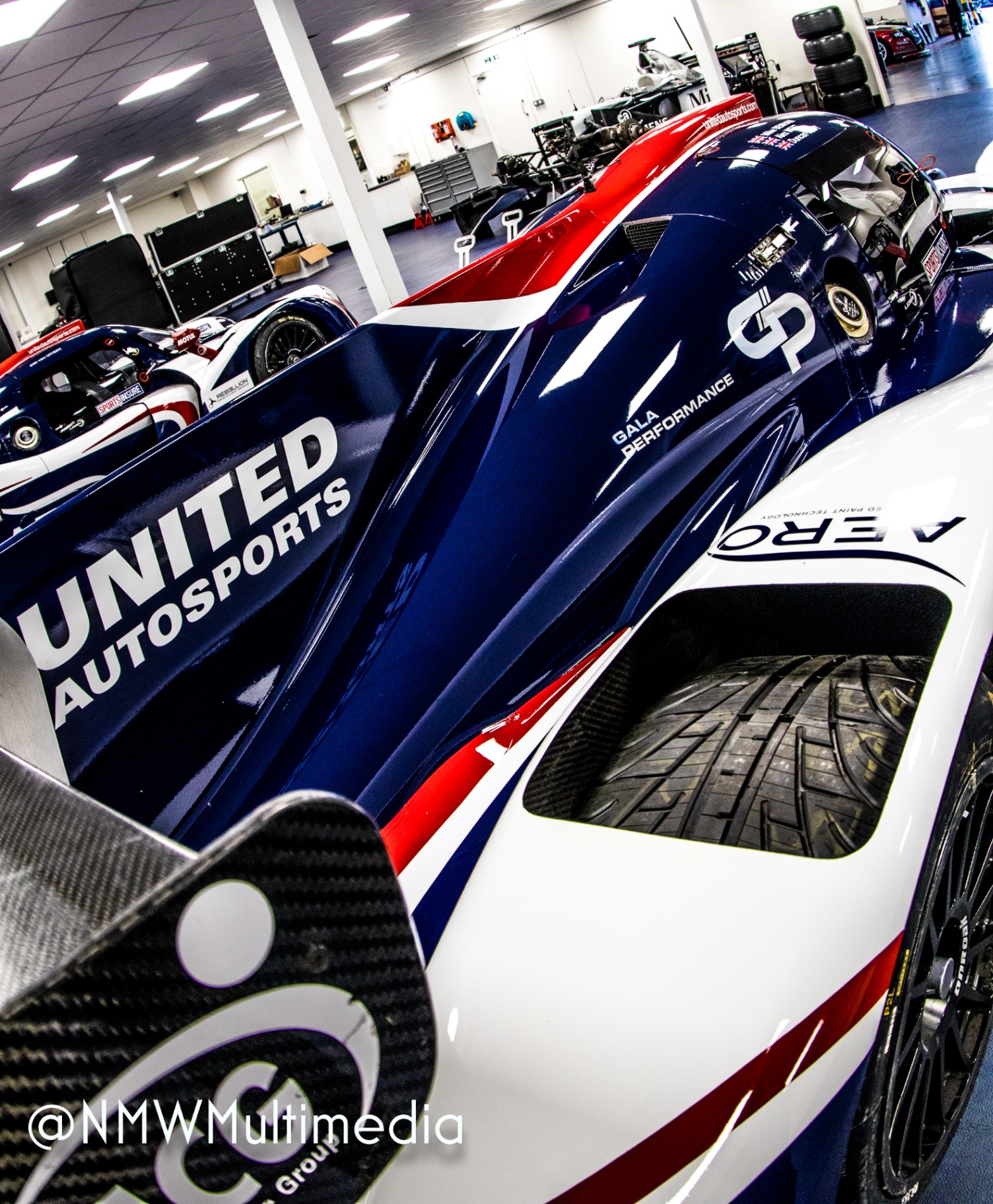 A close, low-angle frame of a United Autosports endurance prototype — sponsor liveries layered like a manifesto.