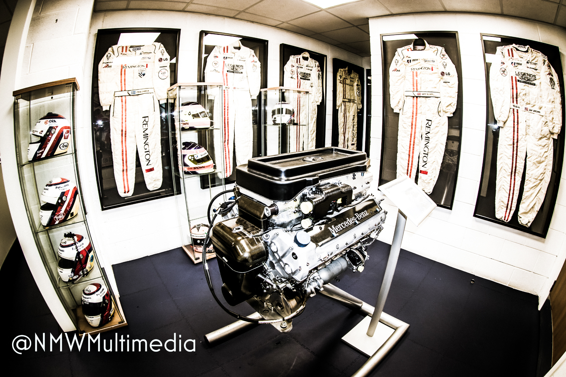 A Mercedes-Benz race engine surrounded by the racing suits of champions.